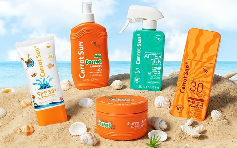 Carrot Sun tanning oil, tanning cream, sunscreen and after-sun standing in warm beach sand among seashells